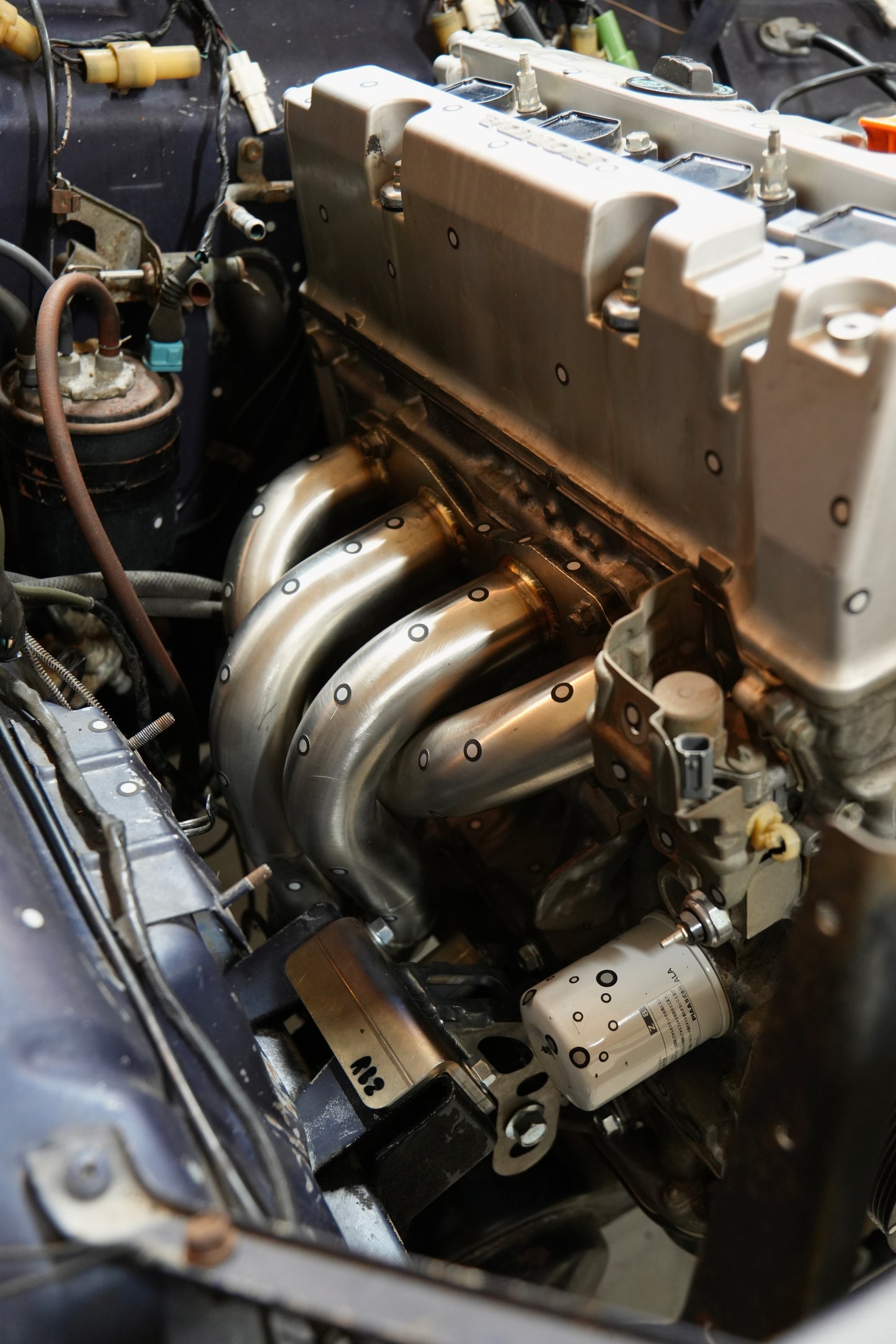 Two-piece K-swap Miata header routed below K24 engine in Suzuki Samurai with RBZ Harmony engine mounts